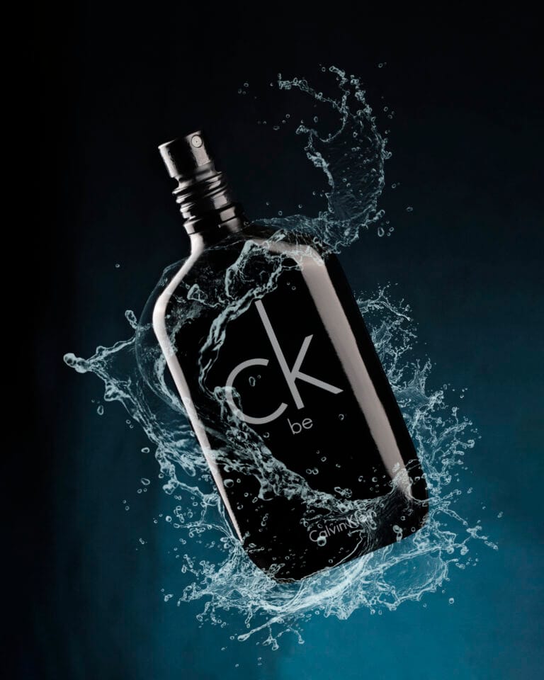 Fotografia de perfume com splash em fundo escuro